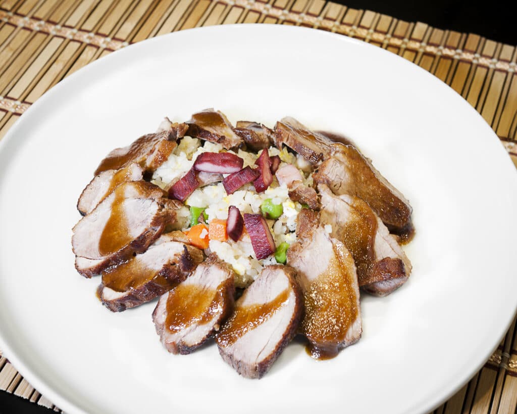 A nicely plated pork dish with rice and sauce.