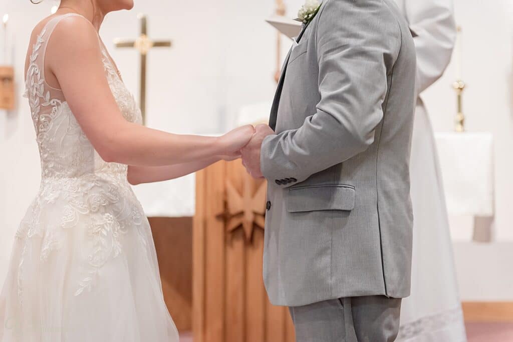 The bride and groom hold hands at the wedding ceremony.