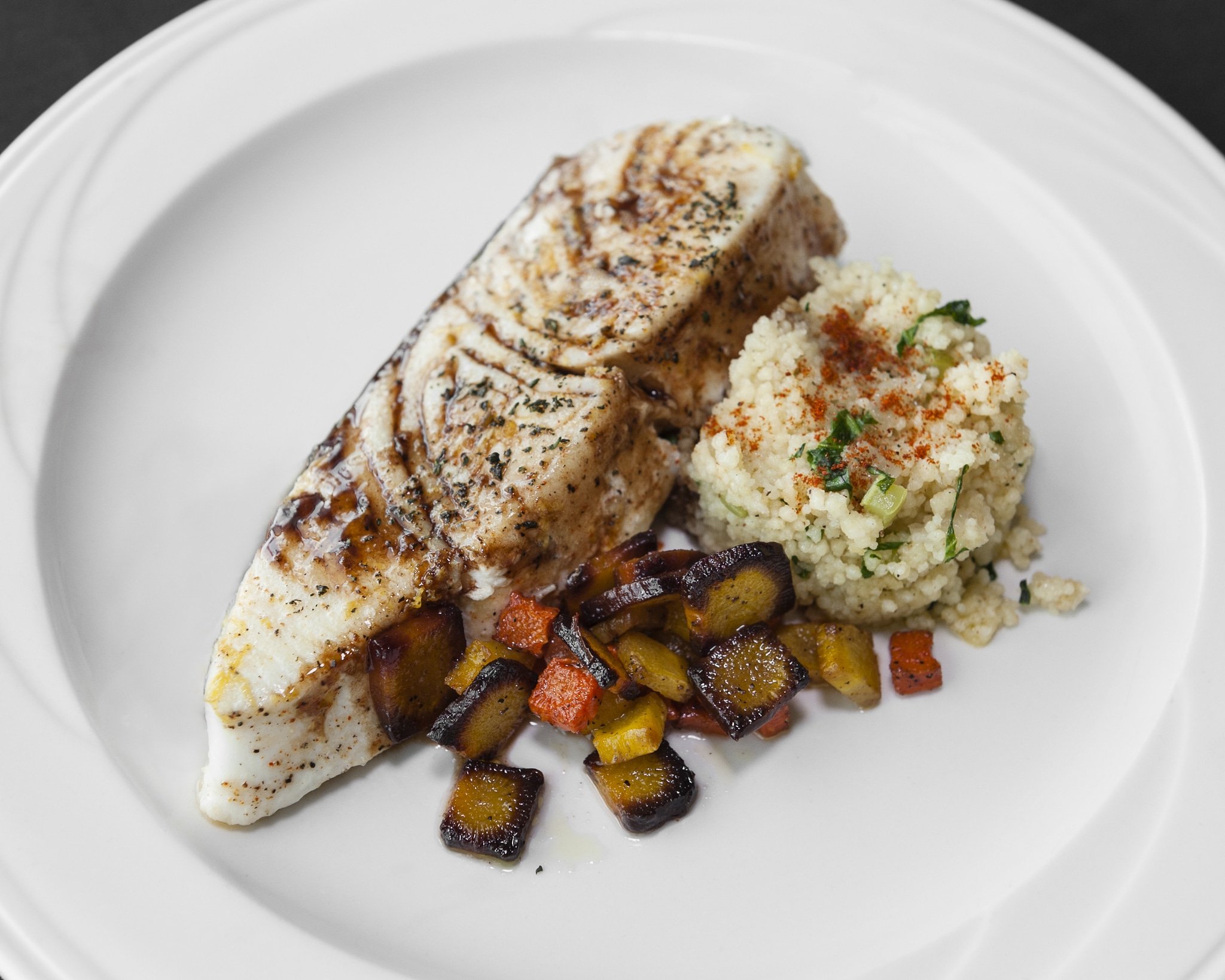 Plated halibut with vegetables and couscous.