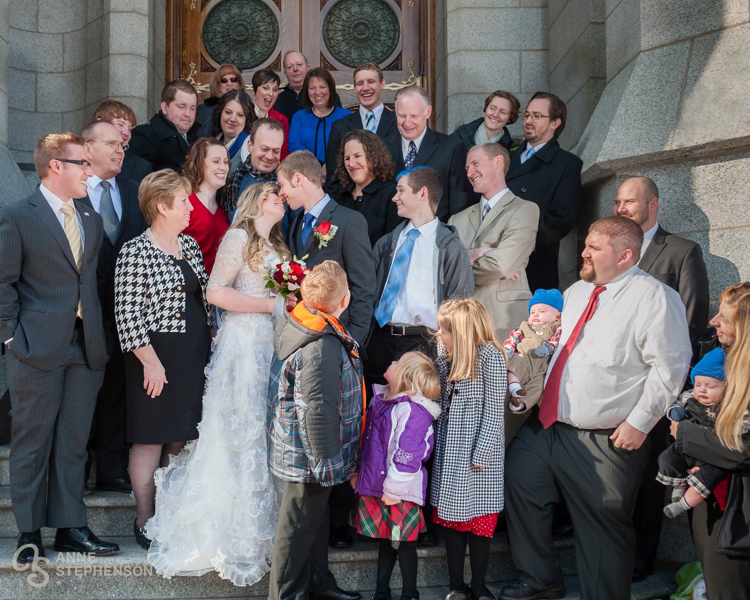Family surrounds the couple on the Temple steps as they start to kiss.