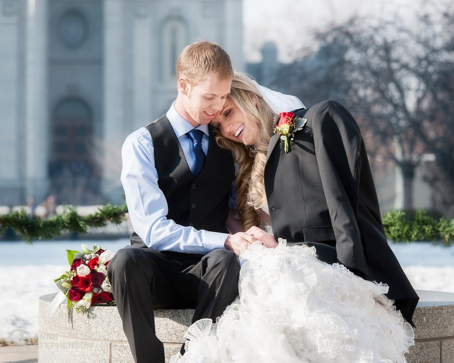 A recently married man places his suit coat jacket over his bride to keep her warm at their winter wedding.