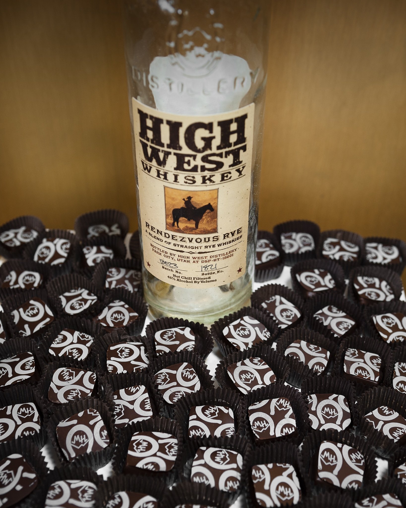 A bottle of High West Whiskey is surrounded by chocolates with the company's logo inscribed on top.
