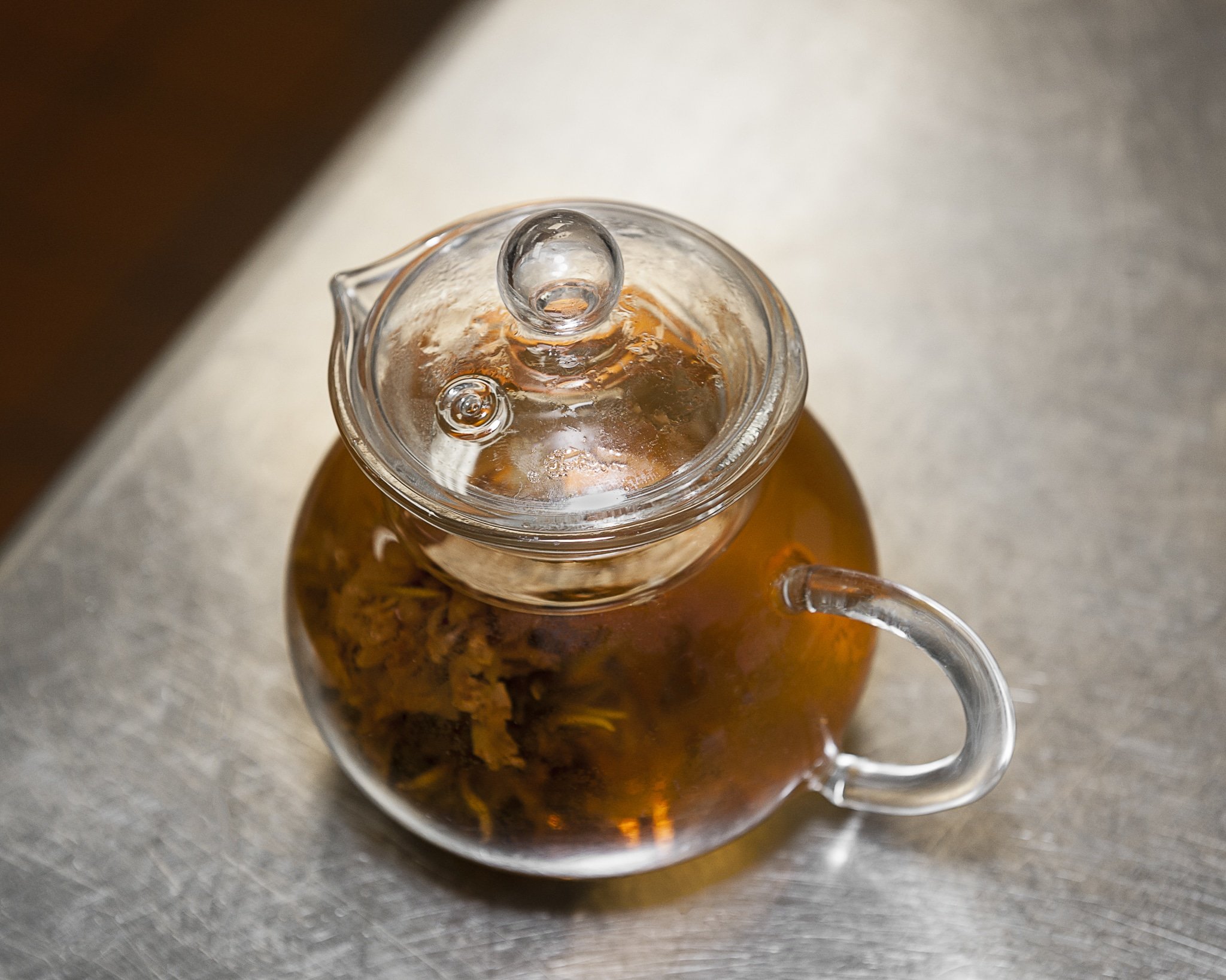A glass tea pot containing a bud-like that appears to bloom when it is steeped.