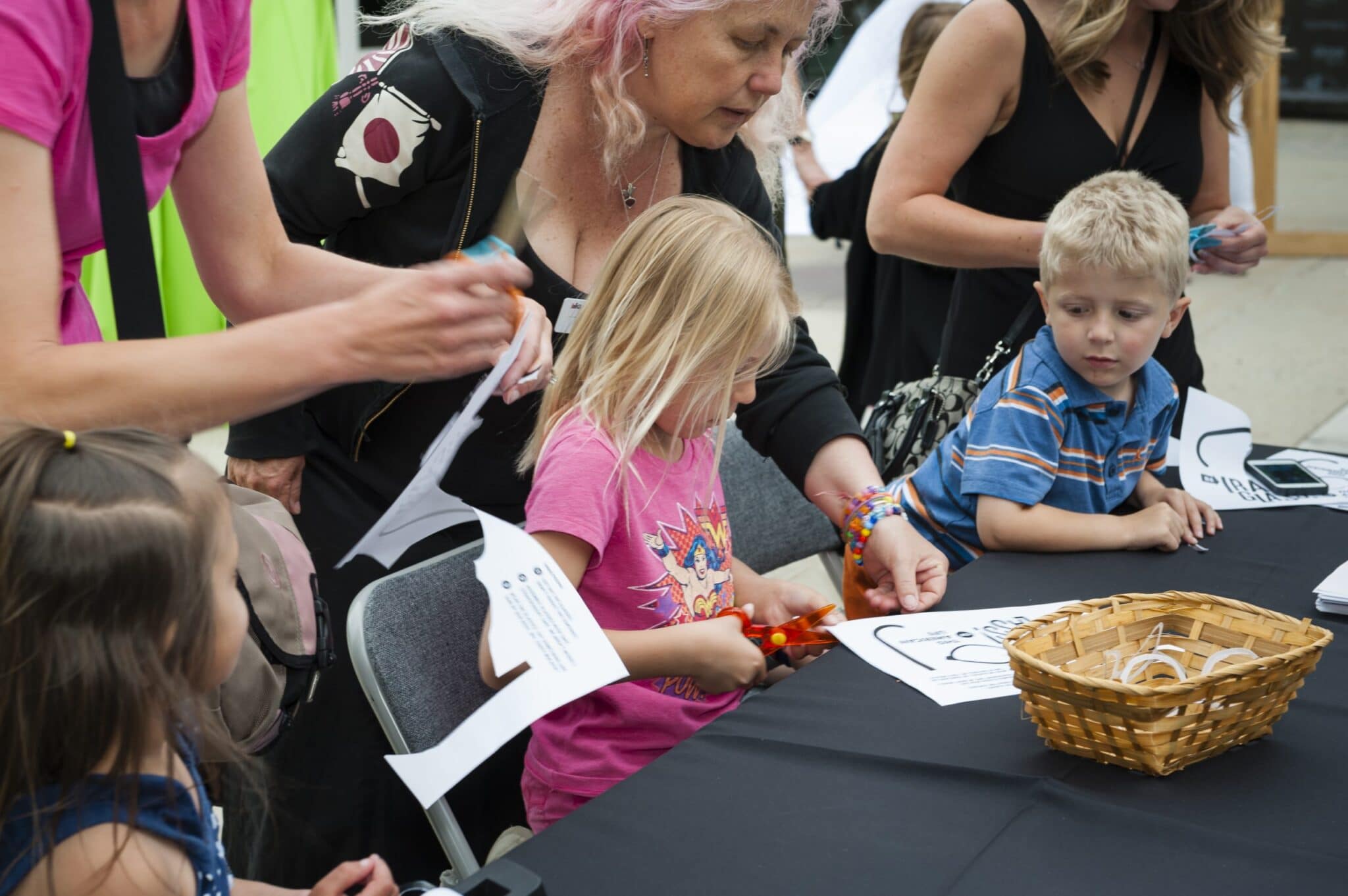 A young girl uses a scissors to cut out a pair of paper glasses at the KUER Summer Sustainer Bash