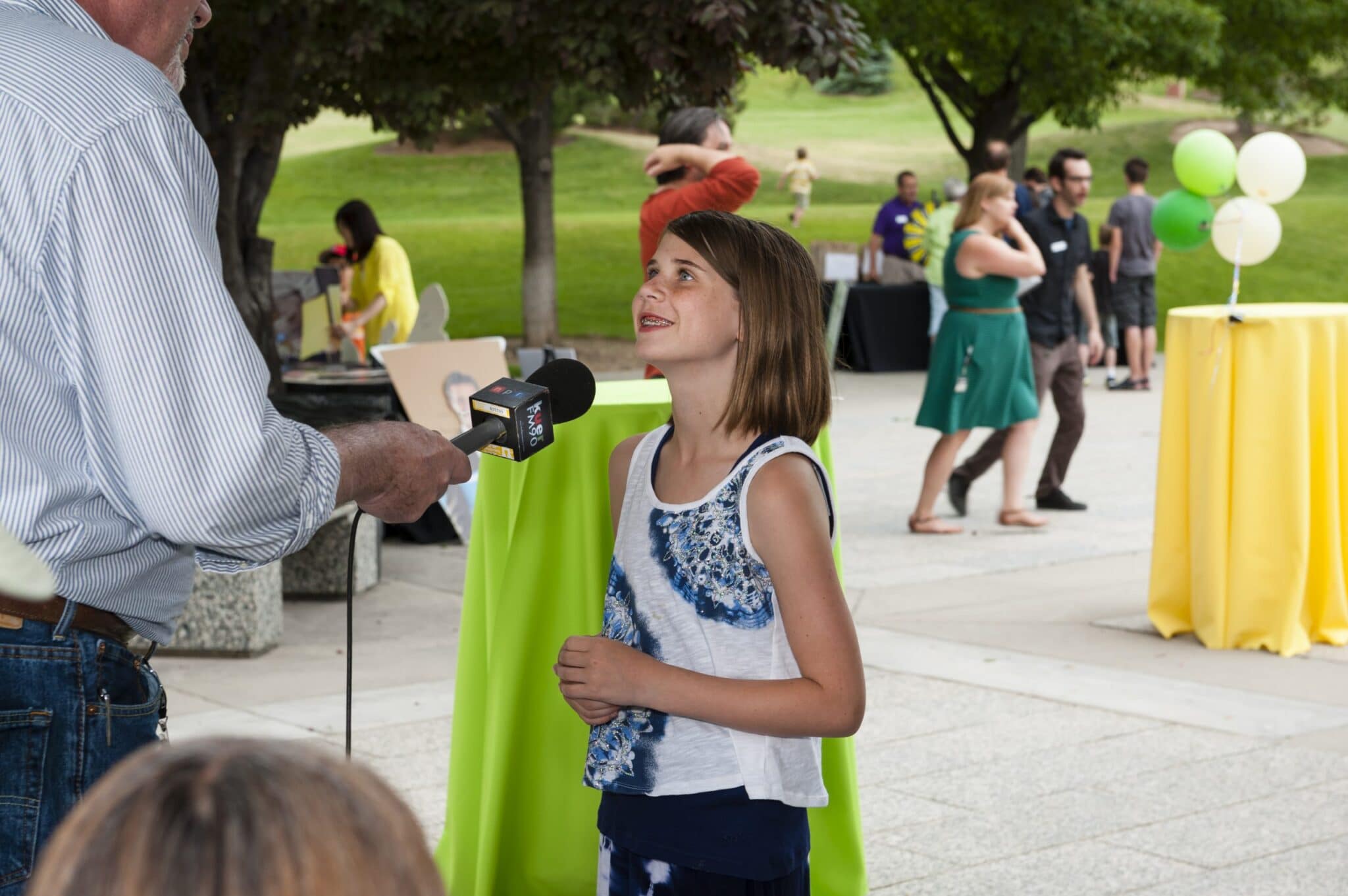 A young girl is interviewed at a public radio sustainer party.