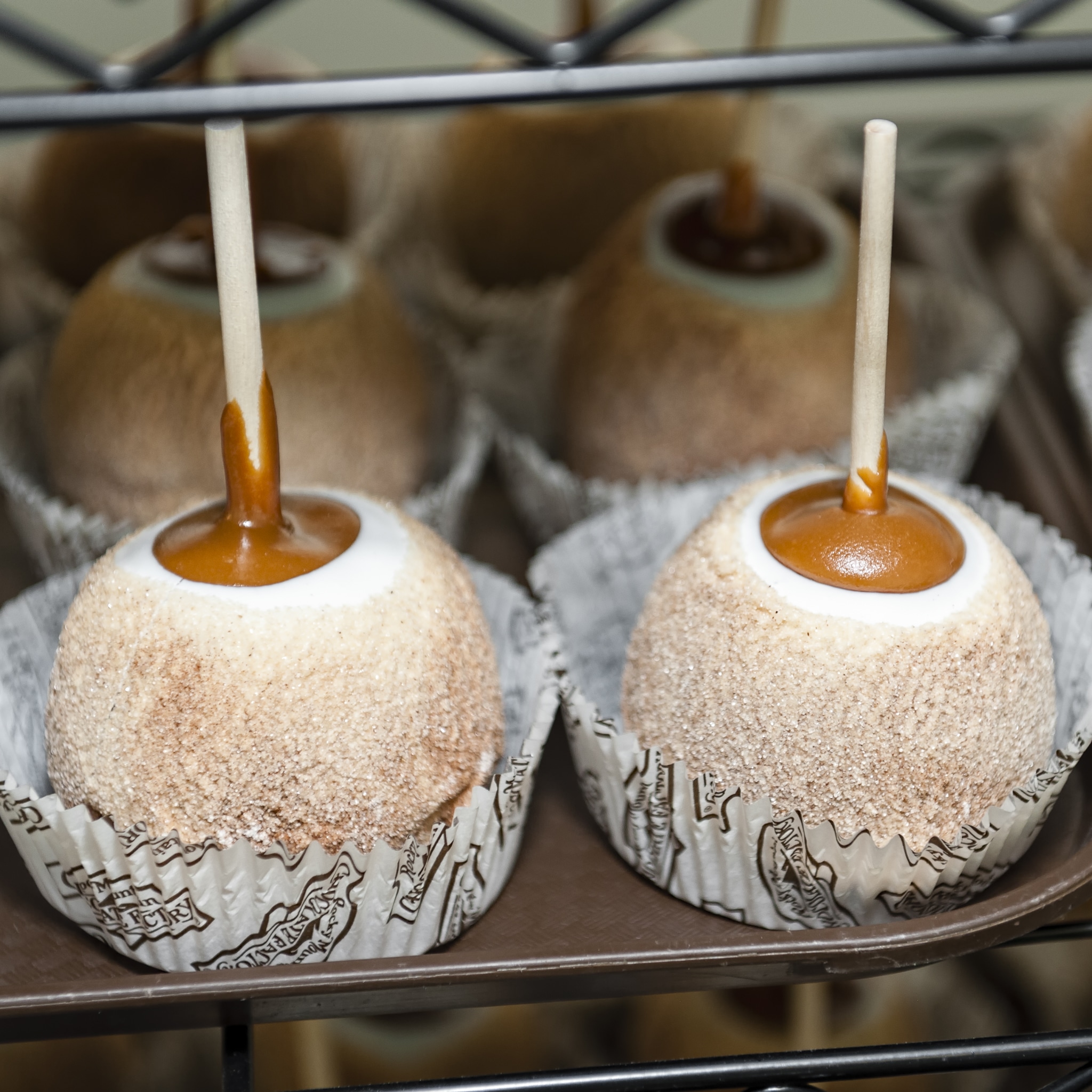 Two large caramel apples coated in sugar and available for the lifting with handy sticks coming out of the tops.