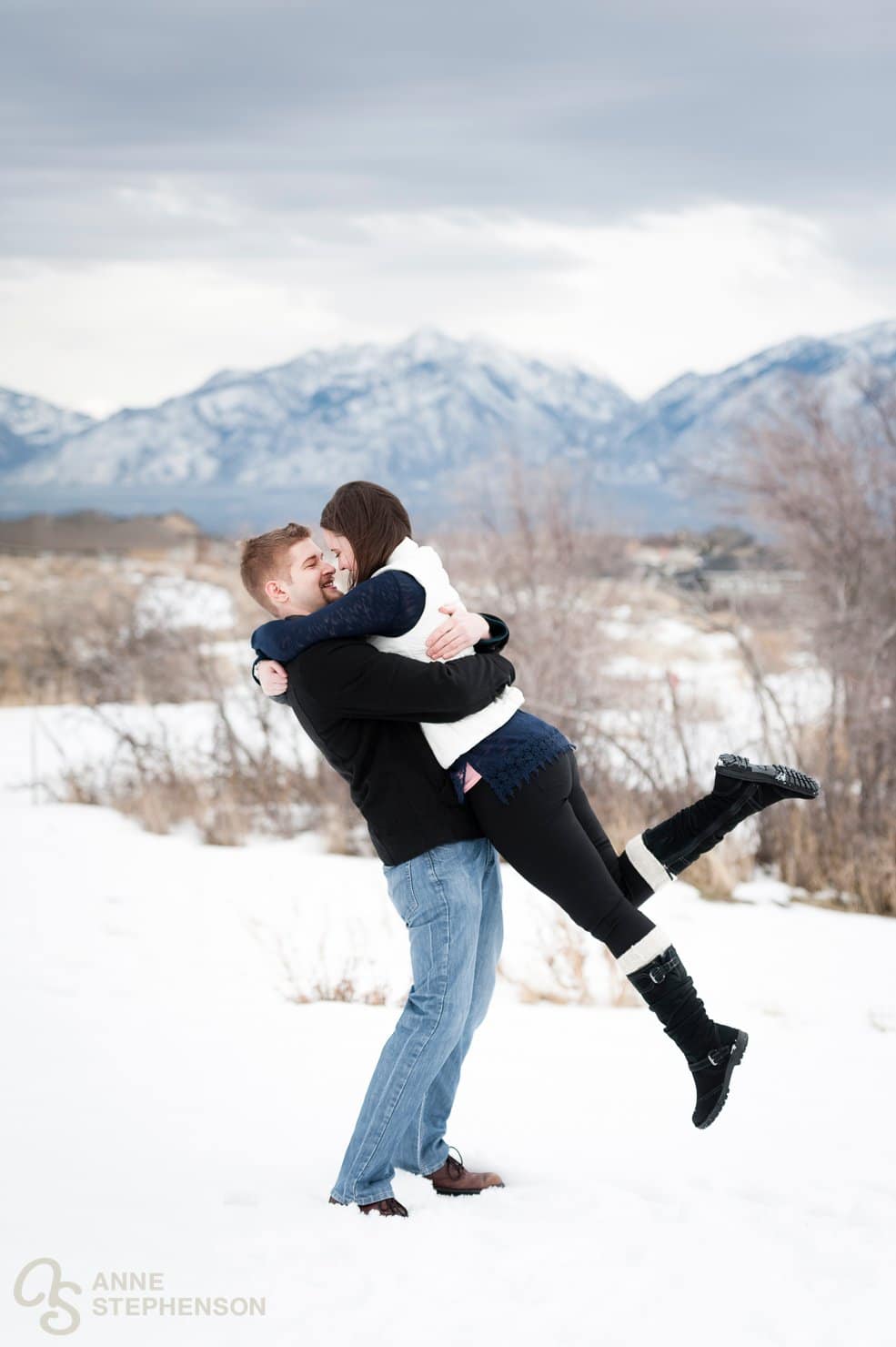 A man holds his fiance and lifts her off her feet during the engagement photo session.