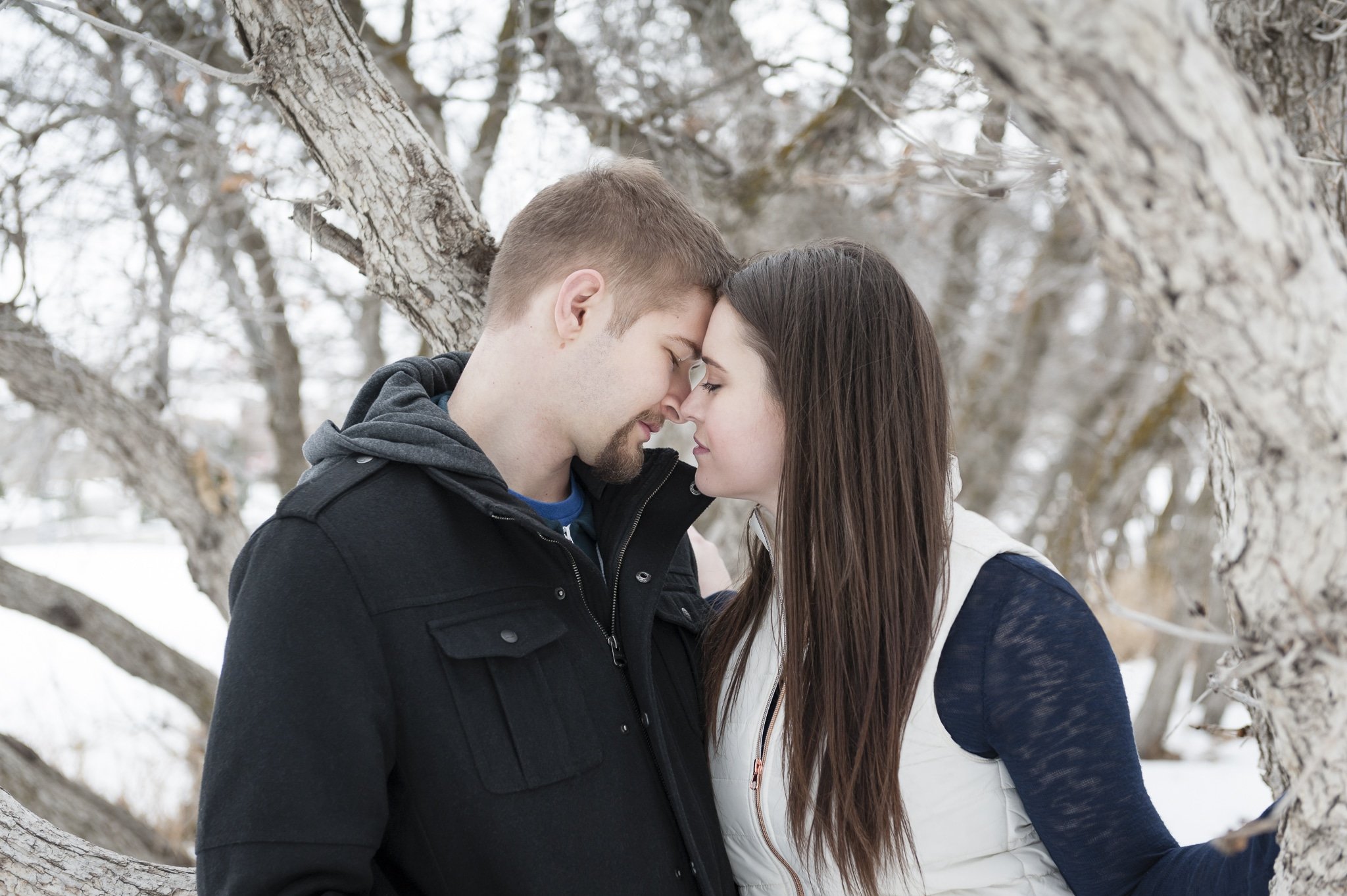 An engaged couple rub their noses together during their photo session in the winter.