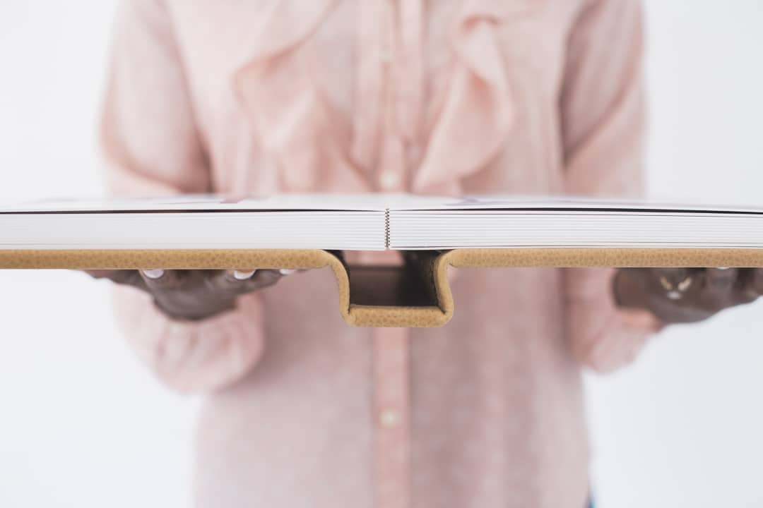 Close up of a woman holding a photo album opened to the center spread.