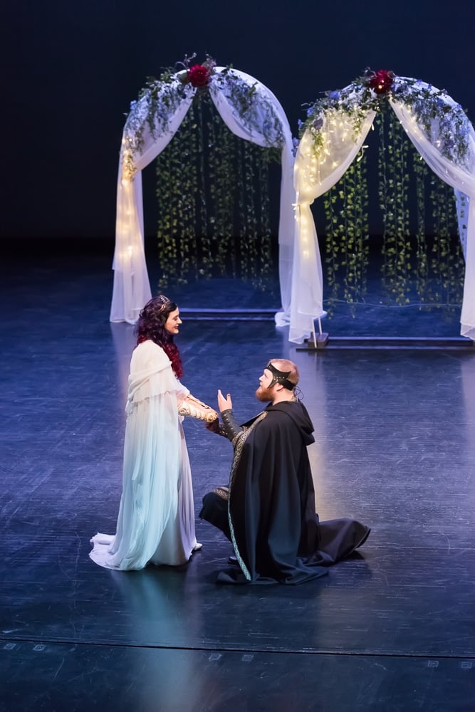 A man and woman on a theater stage during their Dungeons and Dragons themed wedding.