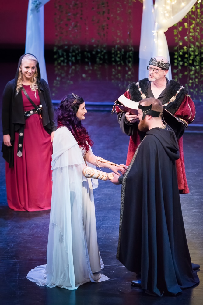 The bride and groom during a Dungeons and Dragons themed wedding hold hands and begin their vows.