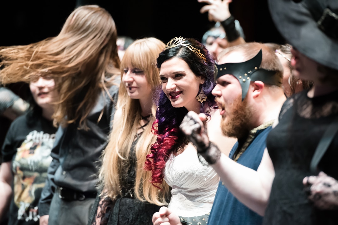 A bride and groom onstage with guests and the band Visigoth.