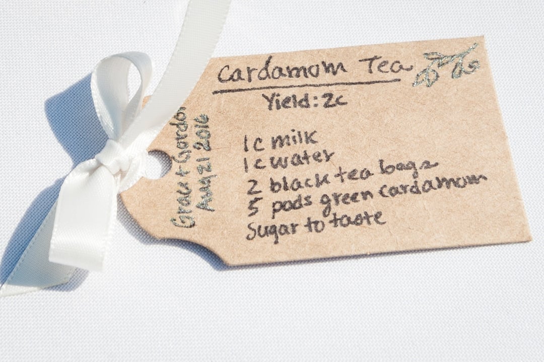 A hand-crafted card with a recipe for cardamom tea tied with a bow.