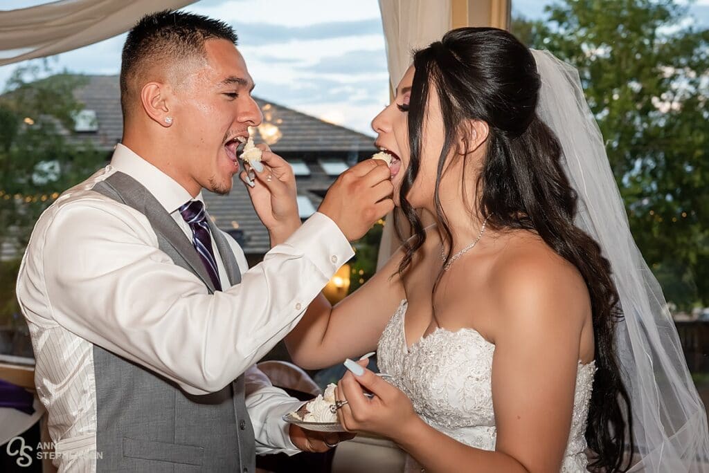 Bride and groom feed each other cake.