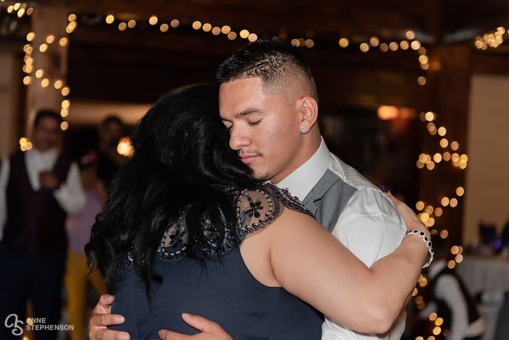 The groom closes his eyes and hugs his mother during their dance together.