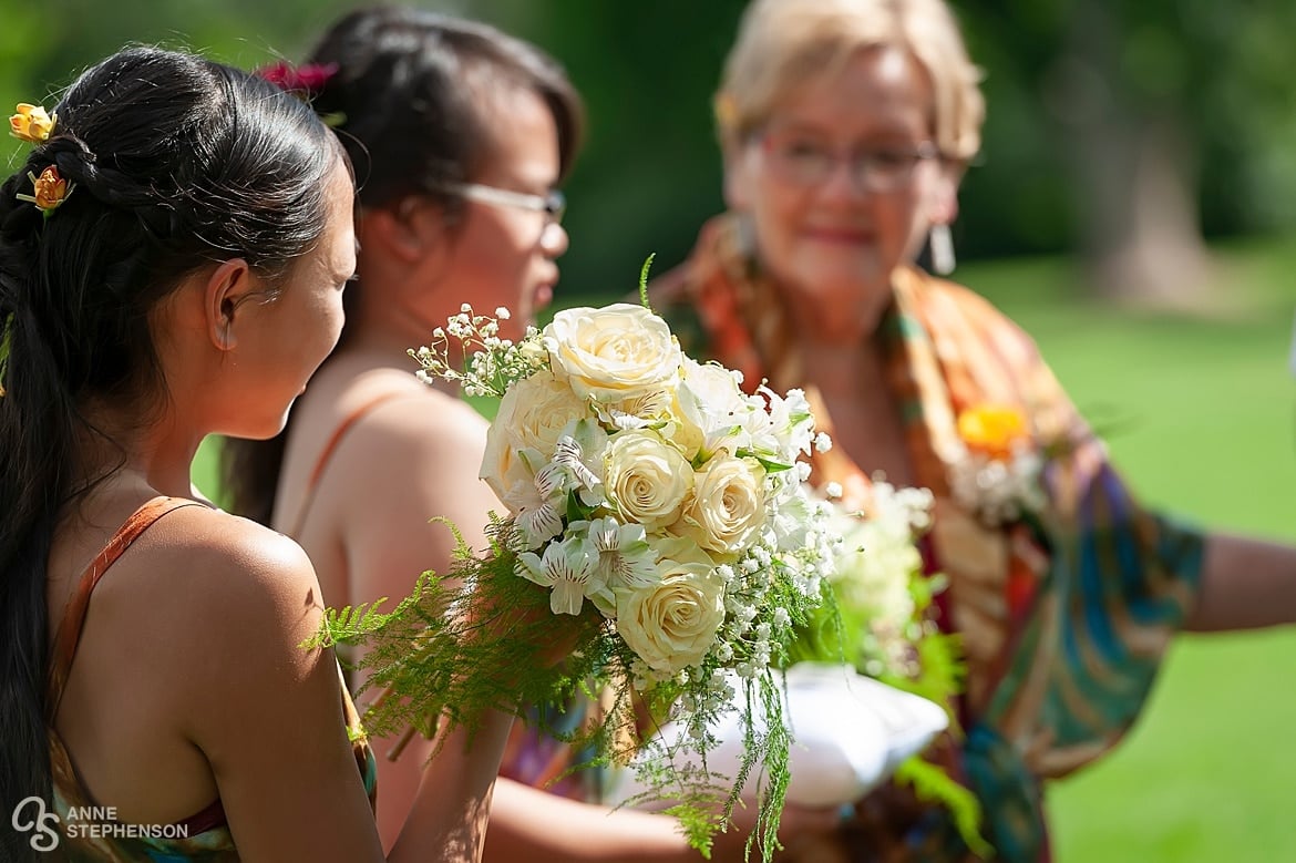 Close up of elegant ivory colored roses that stand out against the bridal company in brightly colored tie-dye attire.