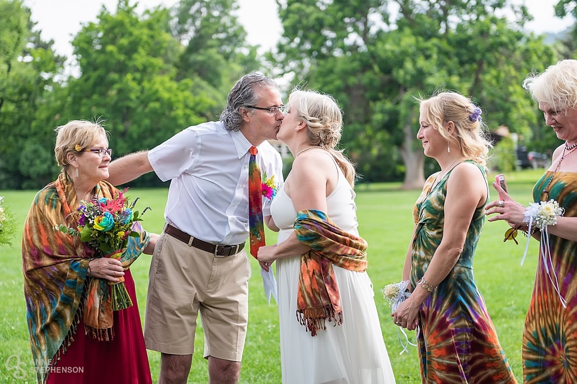 The first kiss as man and wife during a brightly colored tie-dye wedding in Chautauqua Park, Bolder, Colorado.