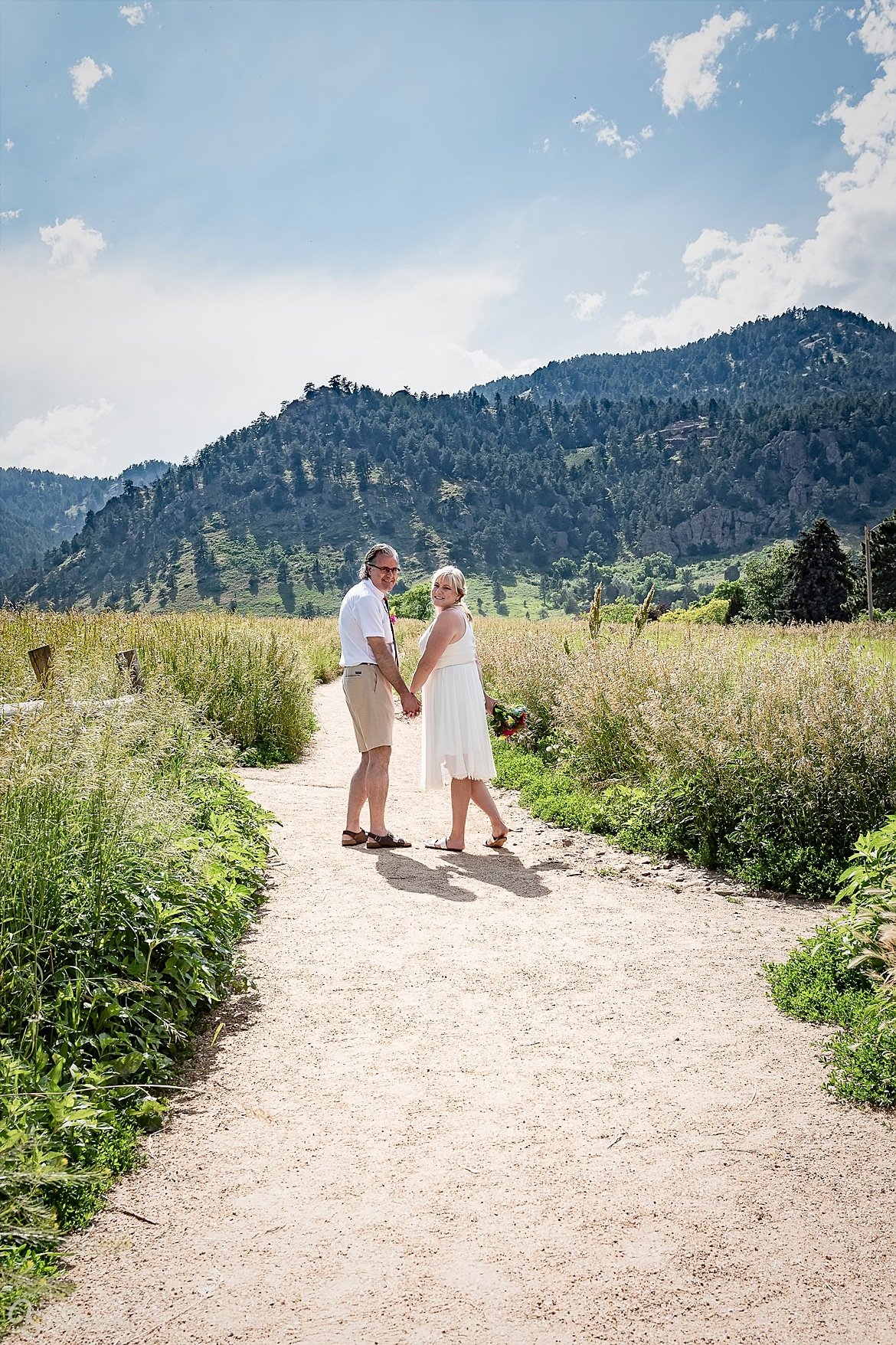 Bride and groom after their tie-dye wedding walk along a path together at Chautauqua Park.