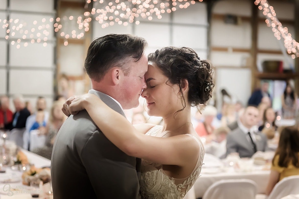 A young couple touch their foreheads together during their first wedding dance.