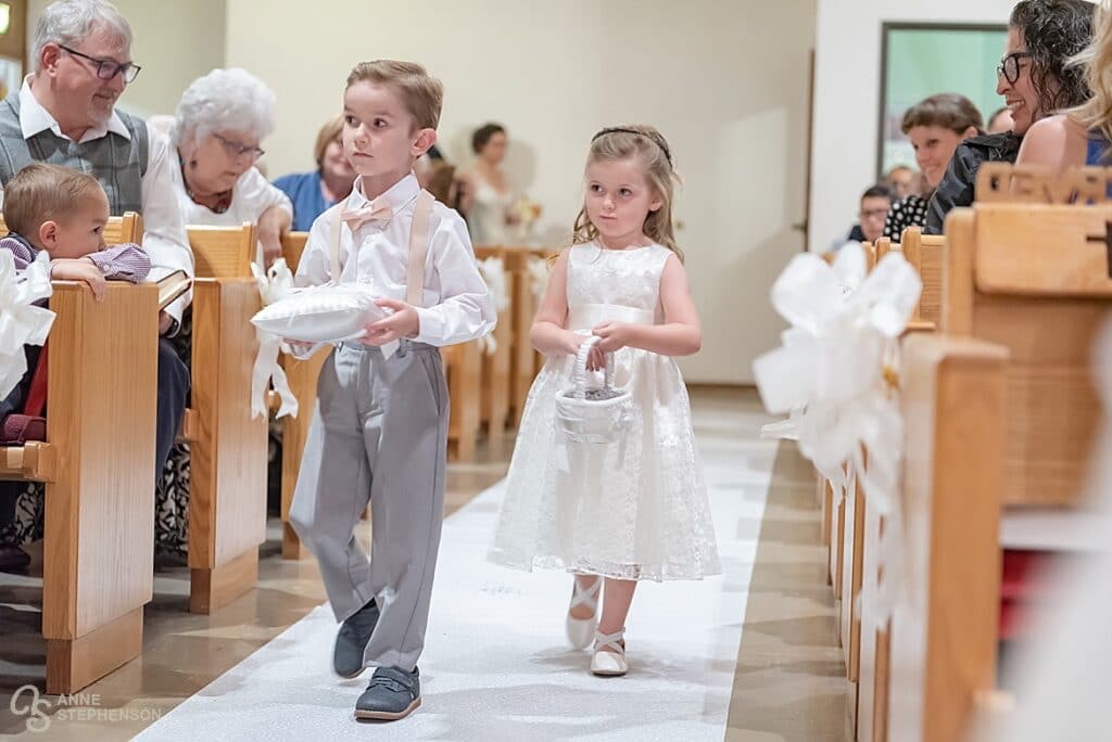 The ring bearer and flower girl proceed down the aisle, marking the arrival of the bride.
