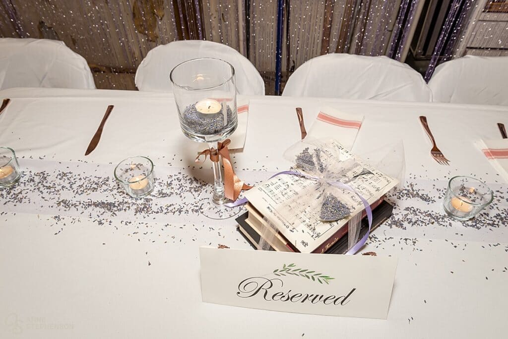 Table decor at the wedding reception includes tea lights, lavender and books wrapped in tulle.