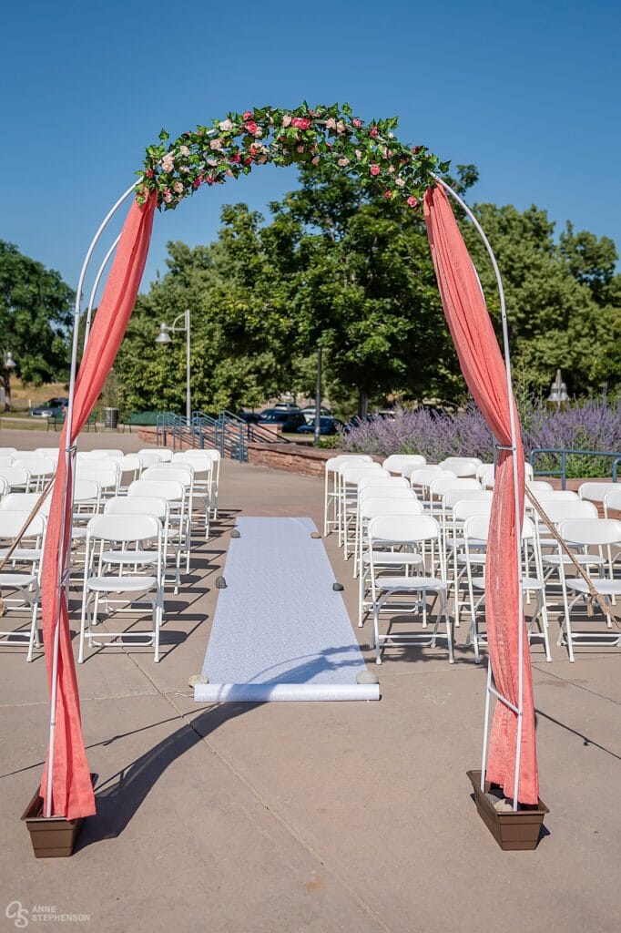 A wedding arbor with peach colored drapes and floral accents.