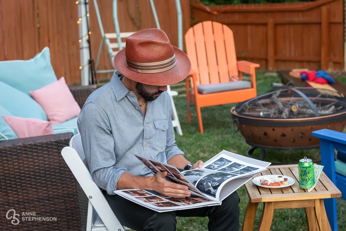 A guest sits in a chair and looks at his friend's wedding album of photos.