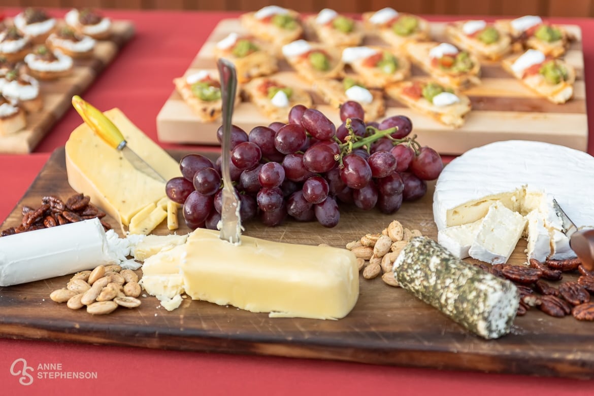 An appetizer plate featuring assorted cheeses, grapes and nuts.