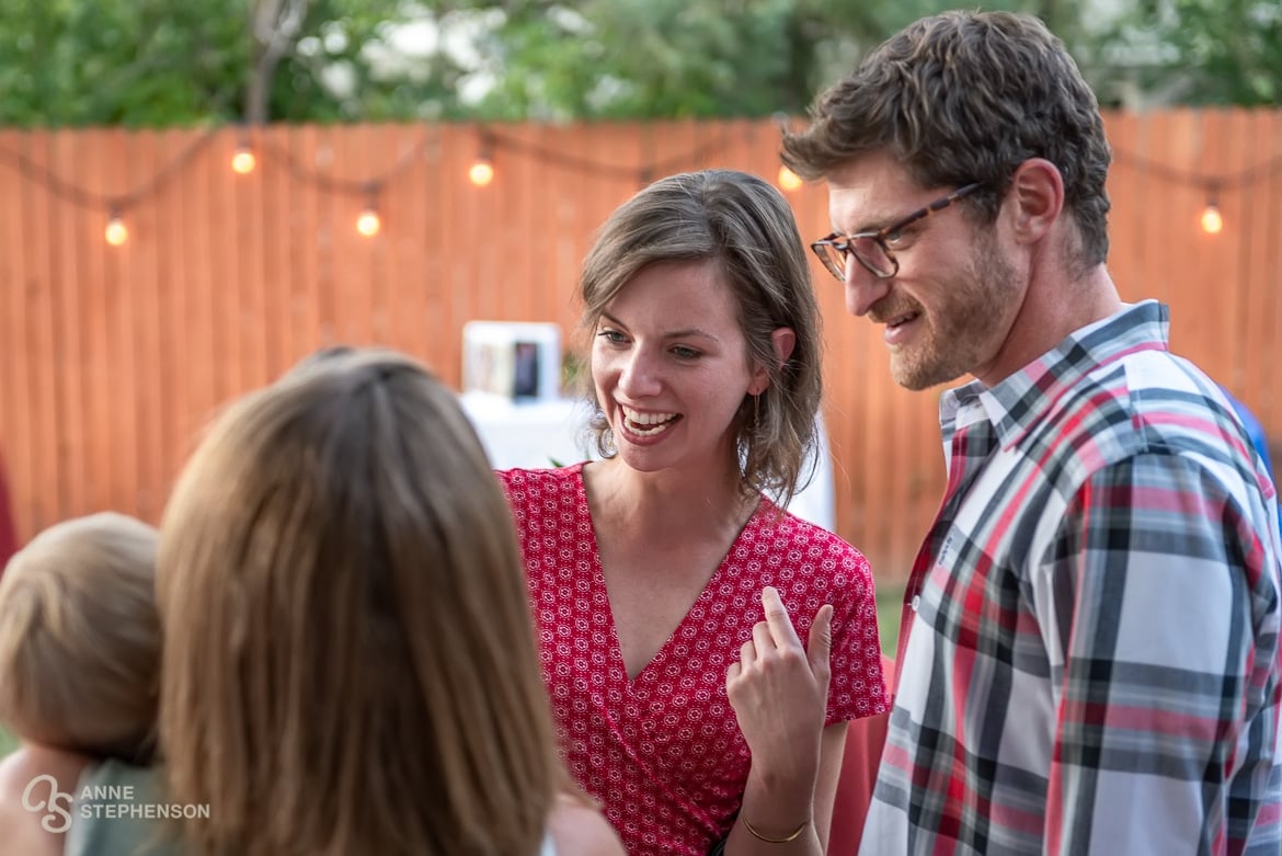 A woman and man are greeted by the hostess at a party celebrating the recent wedding of their friend.