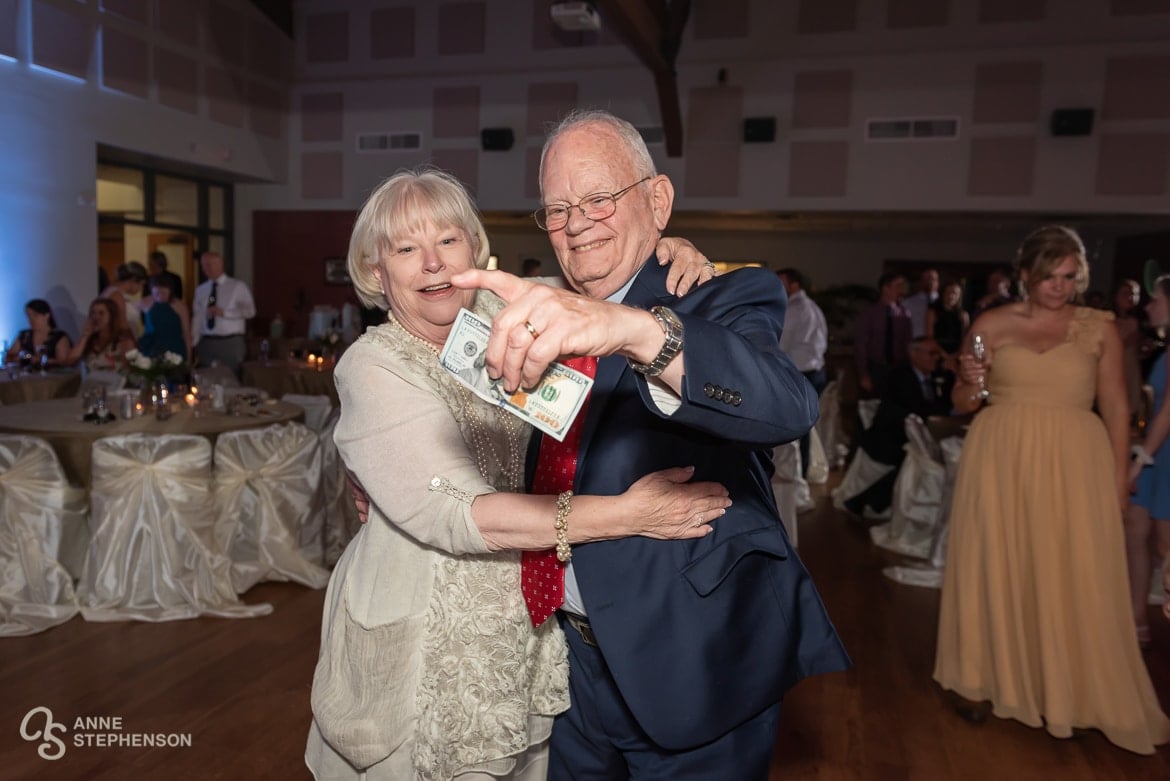 An older couple holds up a one hundred dollar bill that they won during the dance celebrating the couple with the longest marriage anniversary.