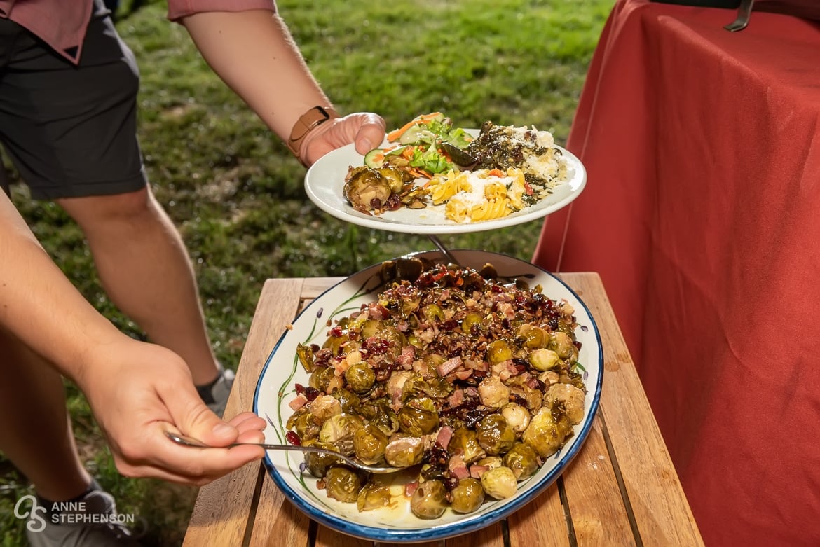 A close up of a woman scooping brussels sprouts off of a platter onto her plate.