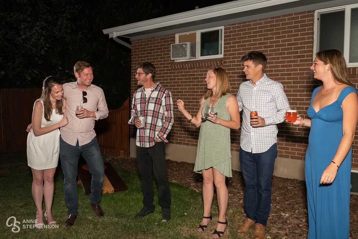 Hostess says a few words to her newly married friends and makes them laugh as the guests look on.