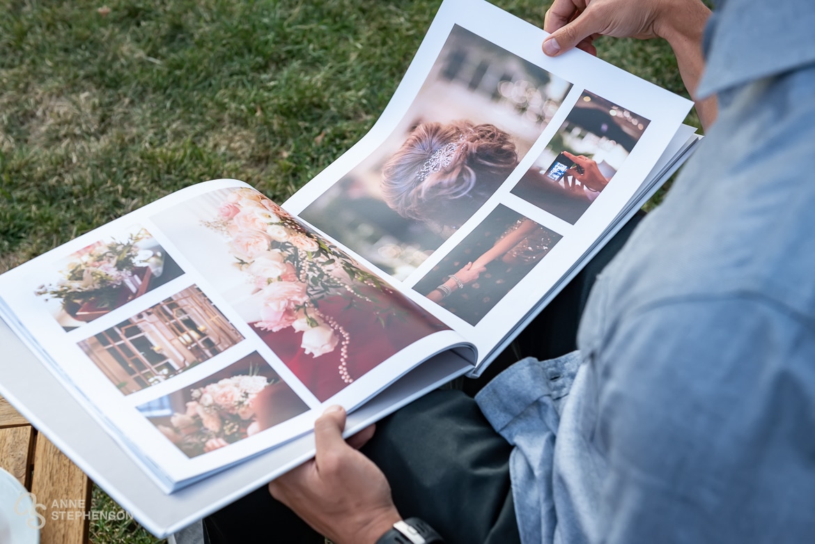 Close up of a guest thumbing through the pages of his friend's wedding album of photos.