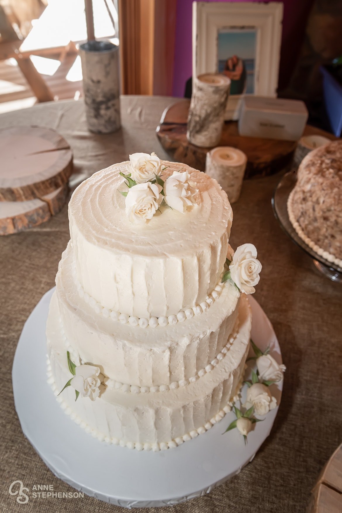 A traditional and elegant three-tiered wedding cake with buttercream frosting and elegant ivory roses here and there.