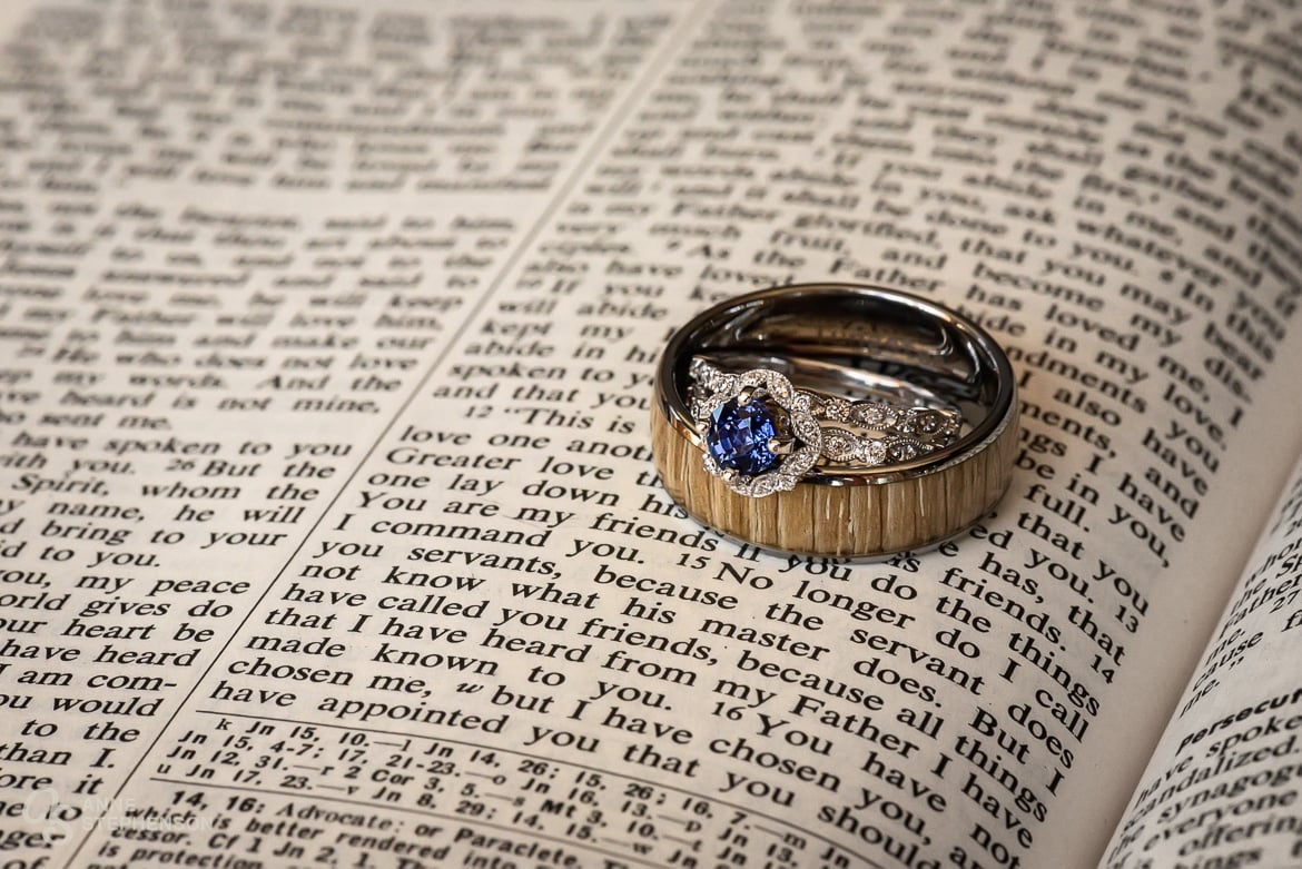 A wedding ring with a sapphire stone in the center on top of a favorite Bible passage.