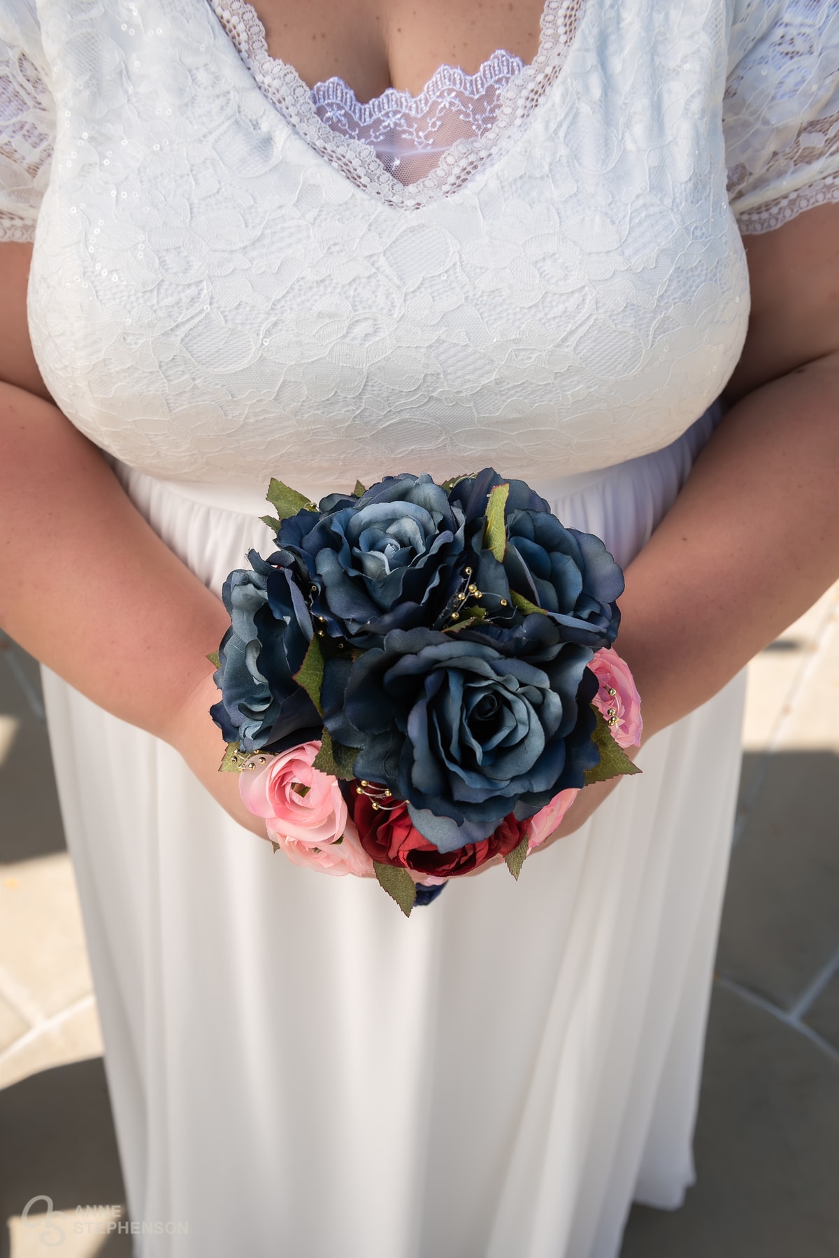 Close up of the bride's bouquet with navy, pink, and red roses.
