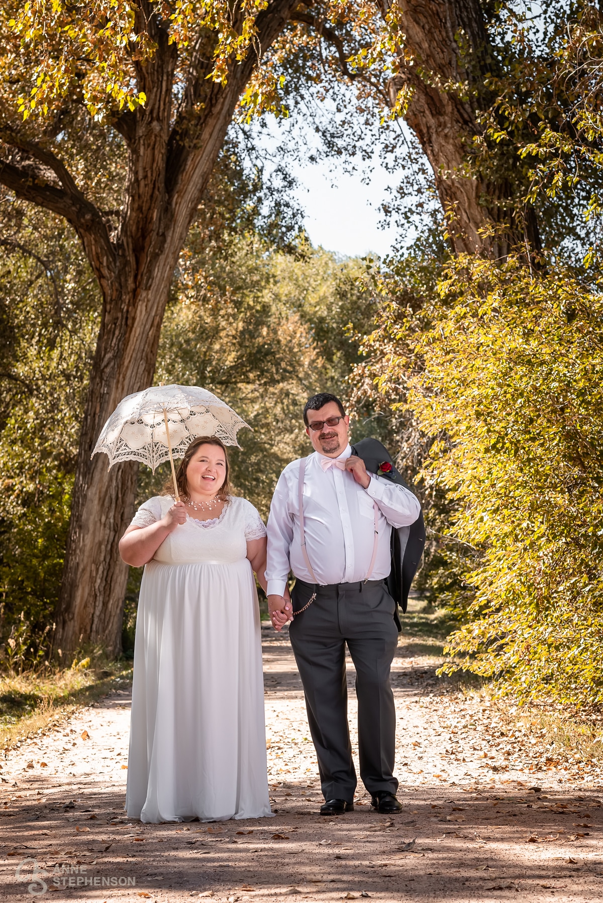 The bride and groom take a stroll under the golden leaves arching over the road next to Boyko Barn.