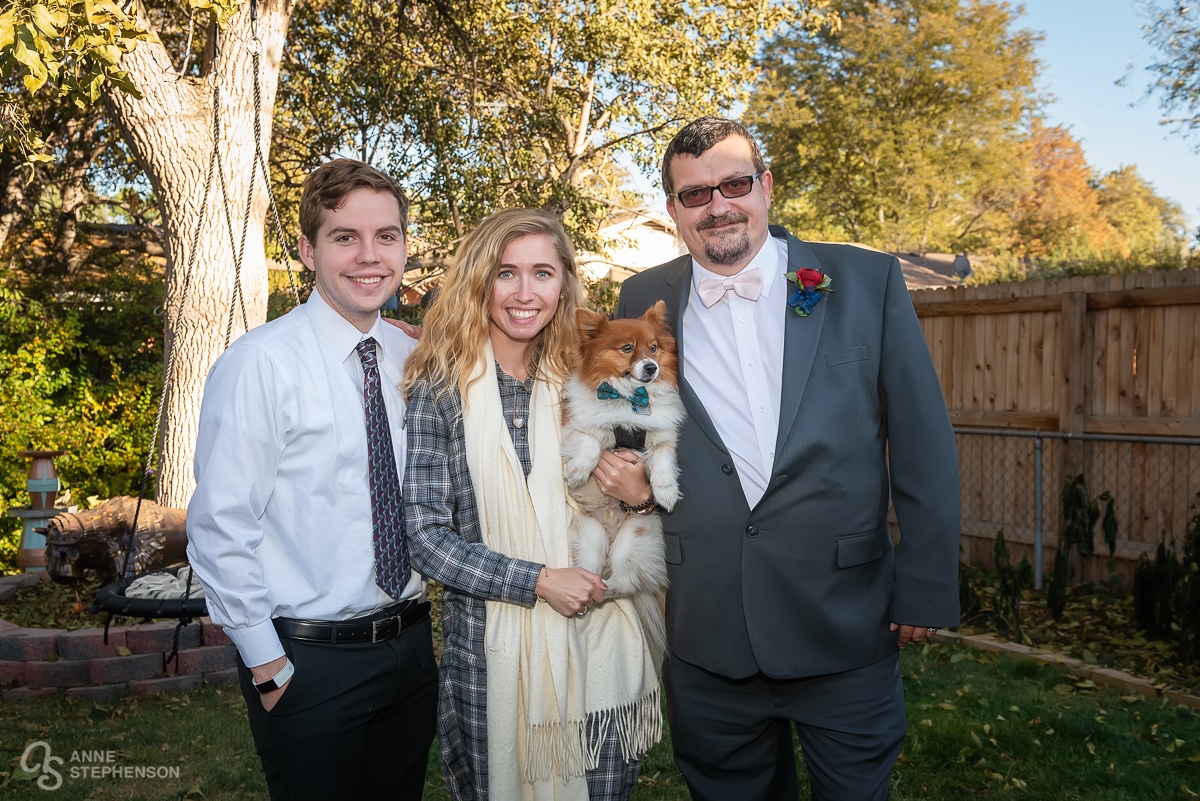 A couple with their fur baby in a bow tie with the groom.