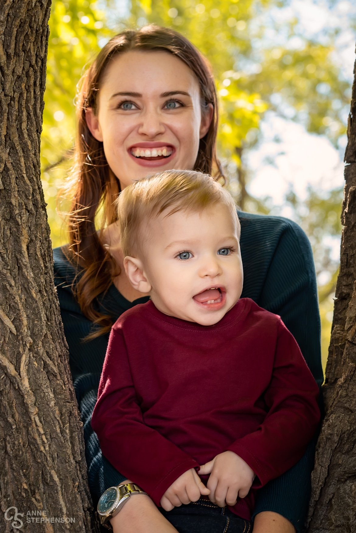 A mother and son between tree branches at their portrait session.