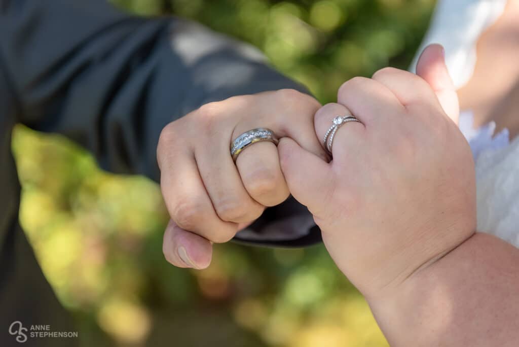 Bride and groom interlock fingers in a pinkie swear
