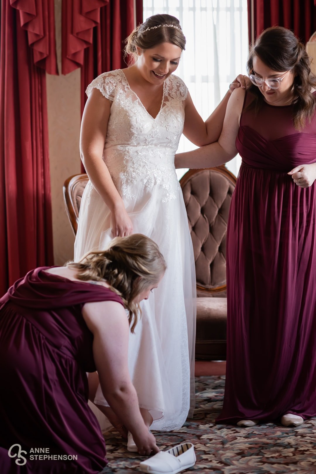 The bride is assisted into her shoes with the help of her attendants.