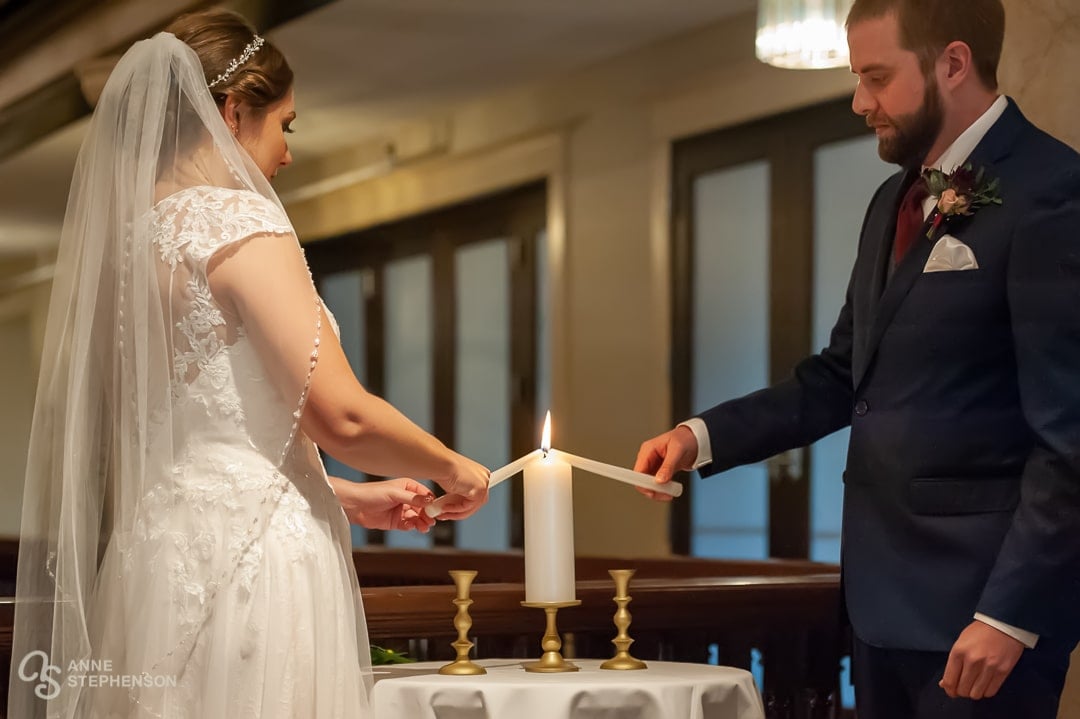 The bride and groom use the light from their individual candles to light a unity candle during the ceremony.