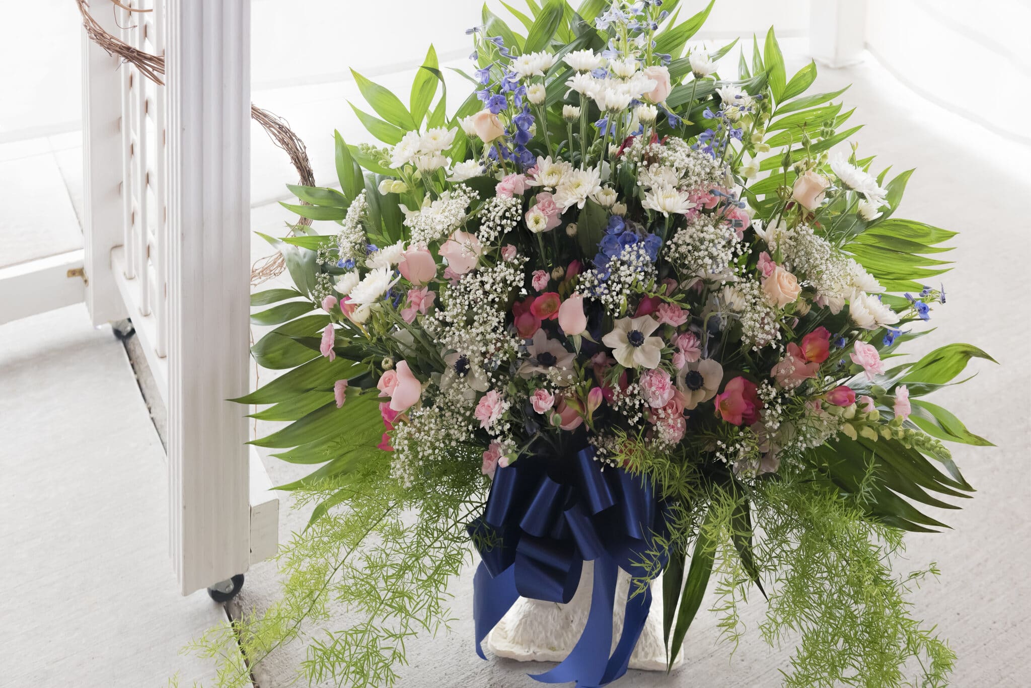 A wedding floral display on the ground at the front of the ceremony includes colors of navy, blue and white.