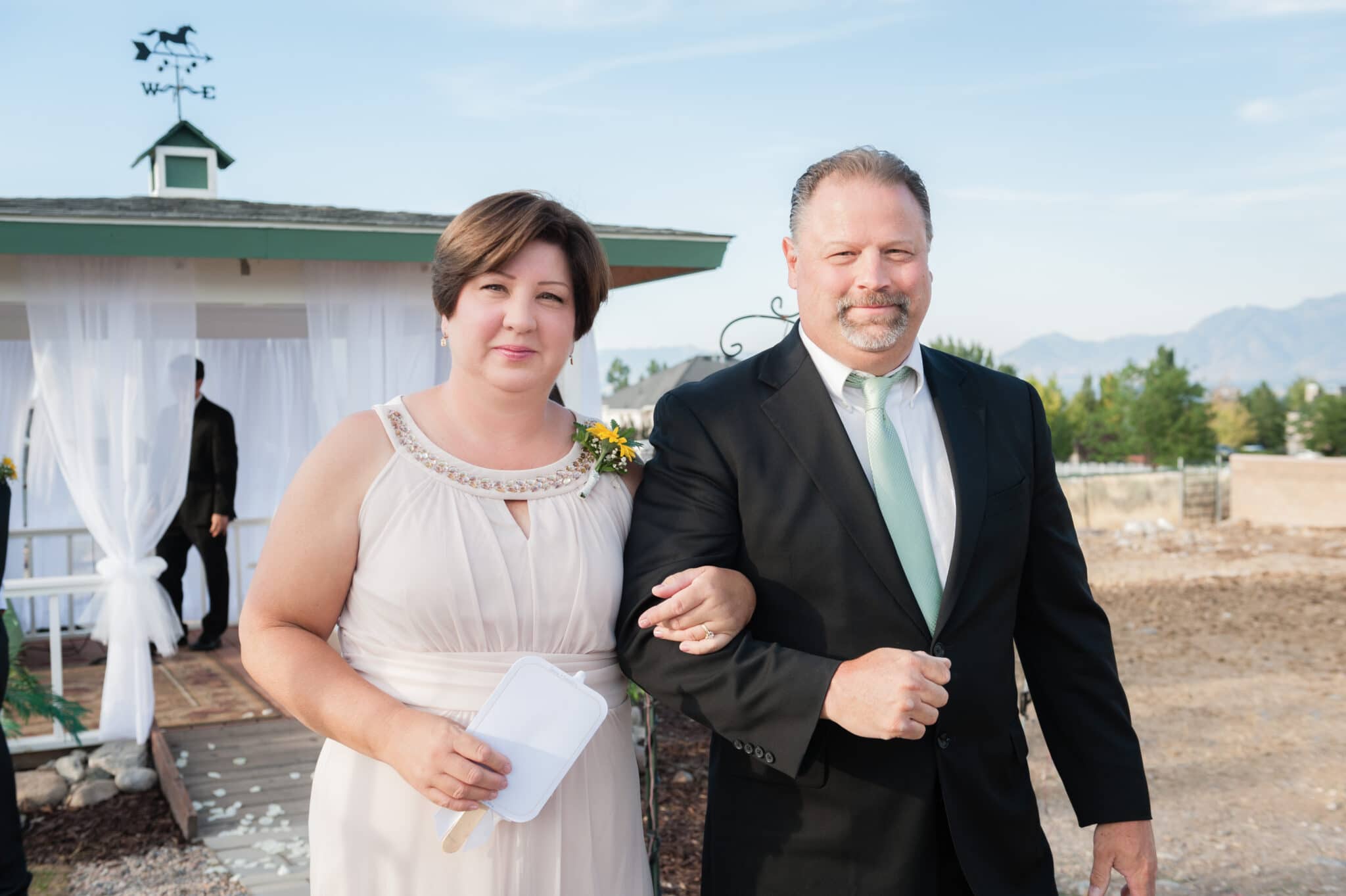 A mother and father link arms and walk during the recessional at their daughter's wedding.