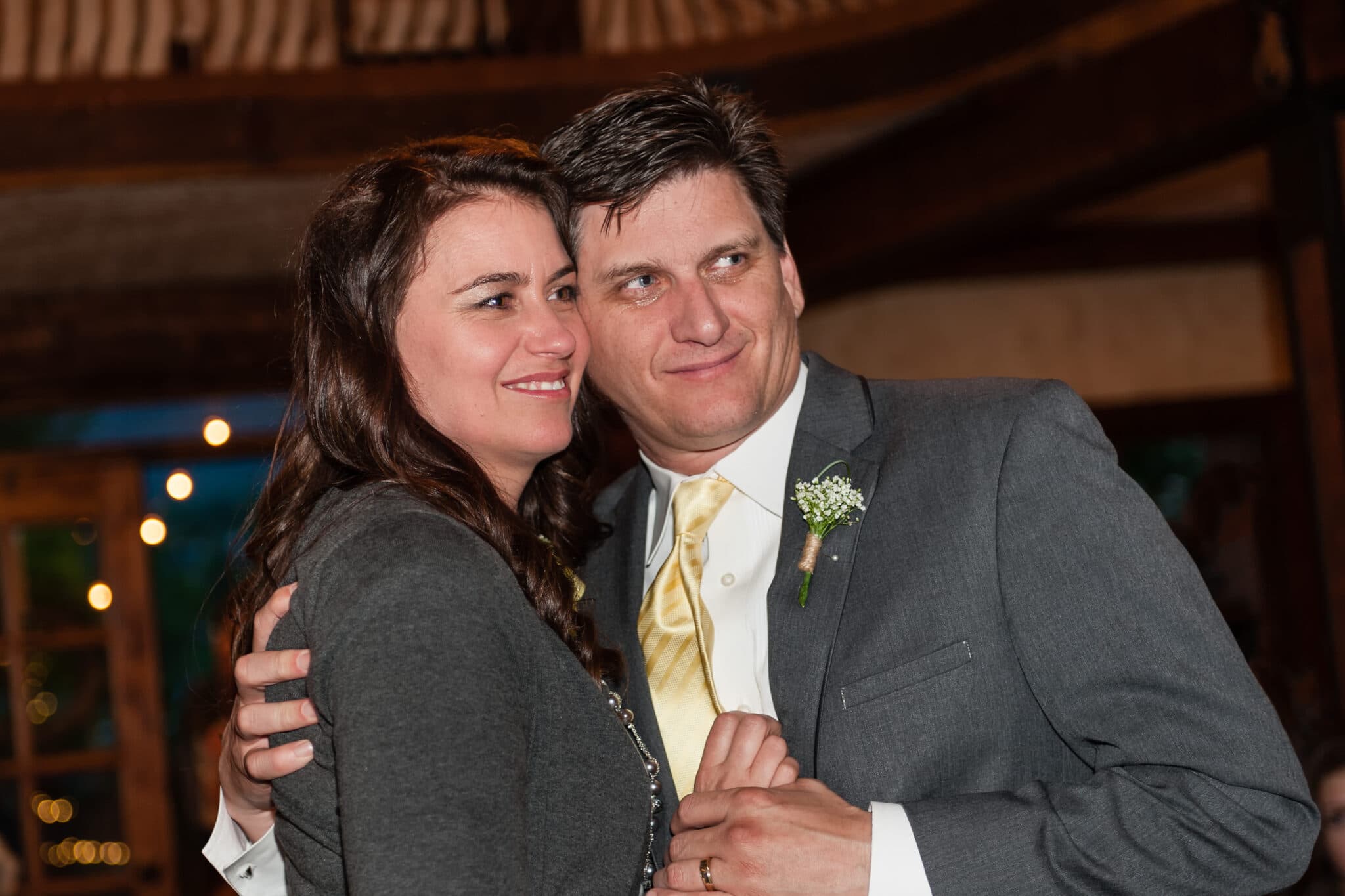 With a tear in his eye, the father of the bride and his wife dance together and look at the wedding couple.