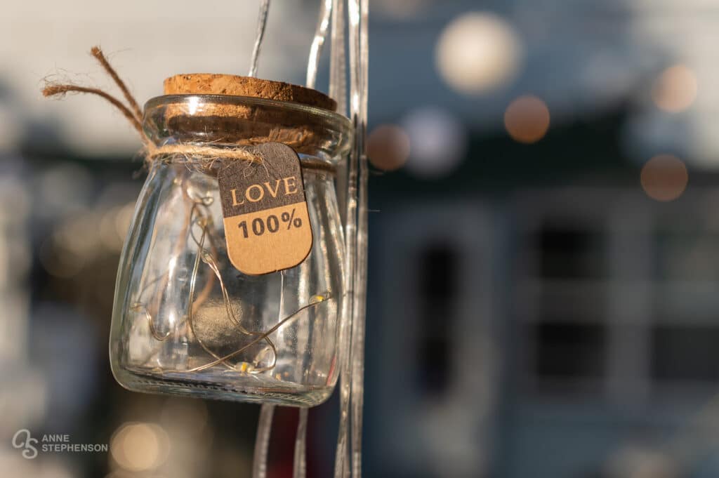 Close up of a jar containing string lights with a label that says "Love 100%"