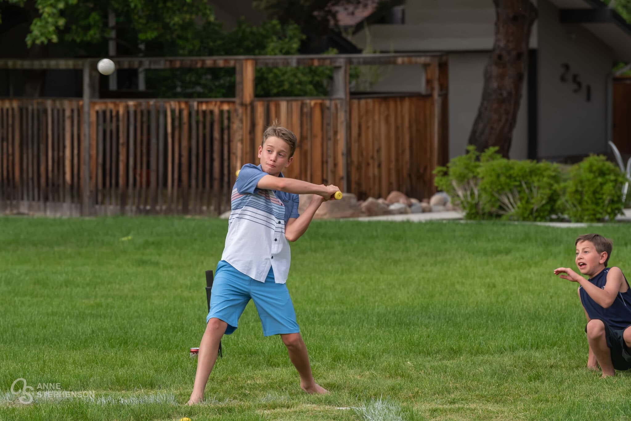 A young teen take the bat and swings during a wiffle ball game.