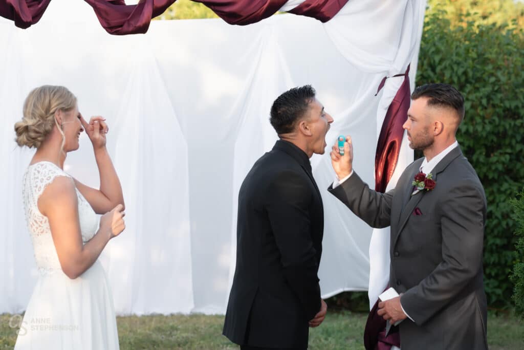 The groom opens his mouth to receive the aerosol breath spray from the groom before the first kiss.