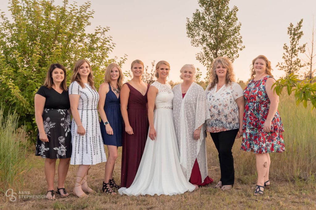The six sisters of the bride and her mother, pose with the bride.