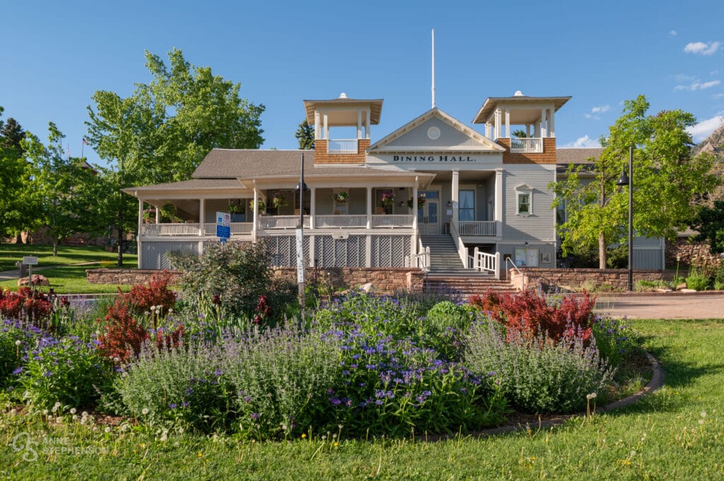 Exterior view of the Chautauqua Dining Hall at Chautauqua Park, Boulder with flowers blooming in the foreground.